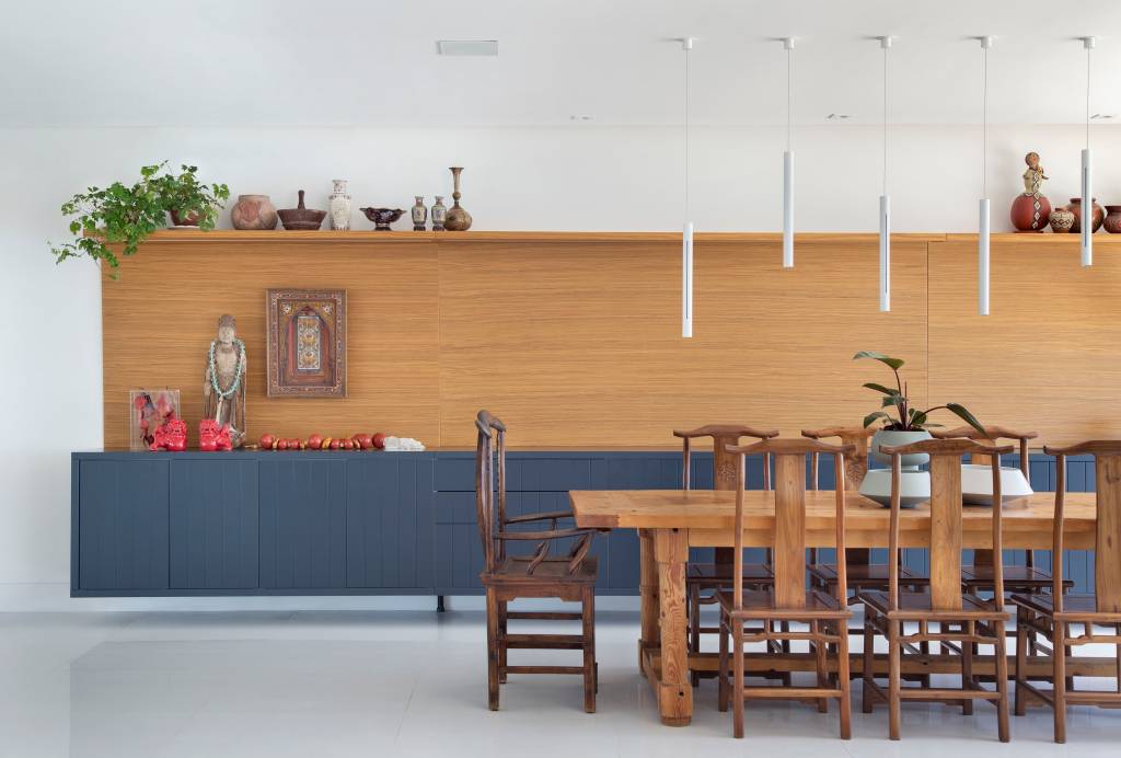 Sala de jantar com mesa e cadeiras de madeira, buffet azul e luminárias