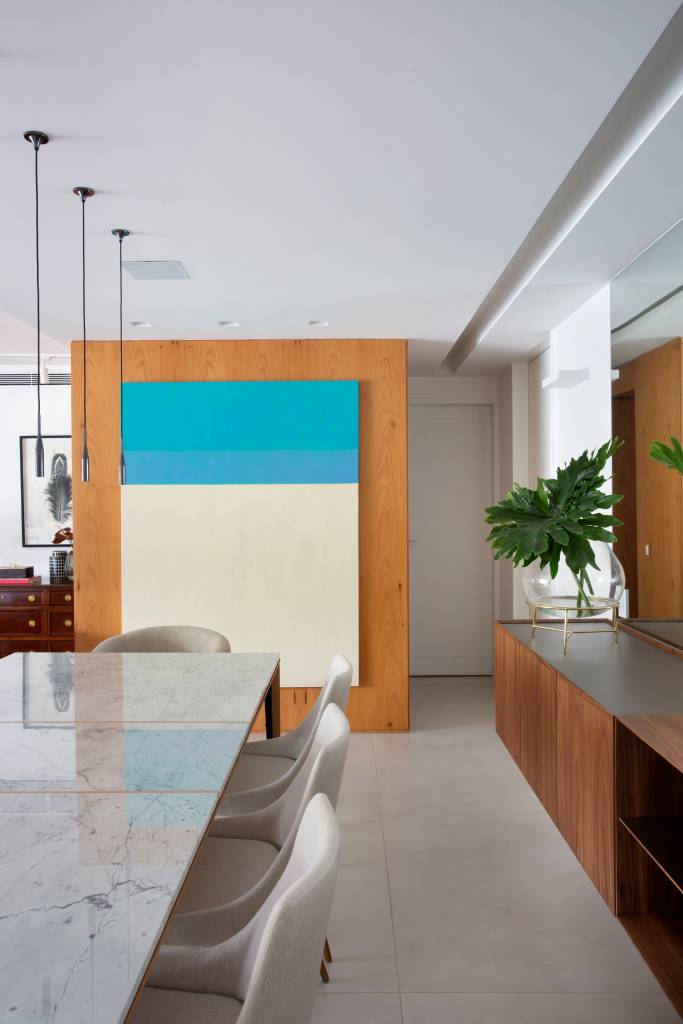 ape-210m-varanda-20m-area-de-lazer-bancada-gourmet-studio-021-arquitetura-12 Sala de jantar com mesa de tampo branco laqueado, buffet de madeira e quadro.