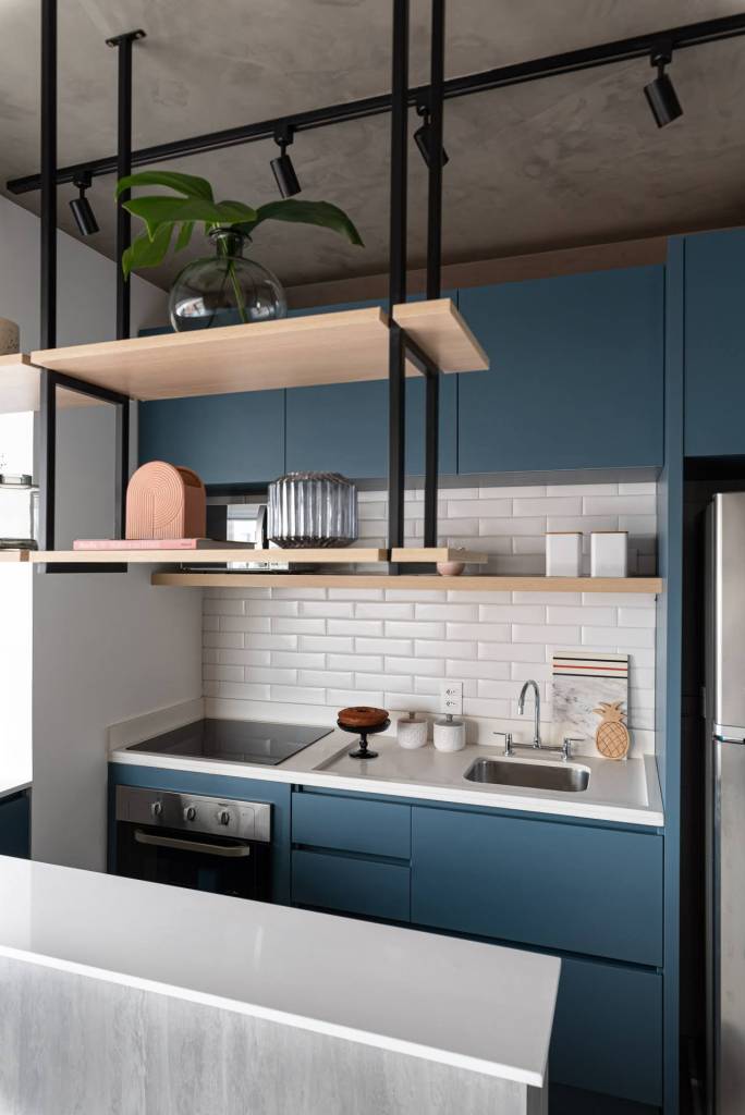 Cozinha com bancada em cimento queimado, marcenaria azul e backsplash de subway tiles