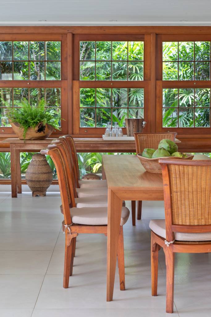 Sala de jantar com mesa de madeira retangular e cadeiras de madeira.