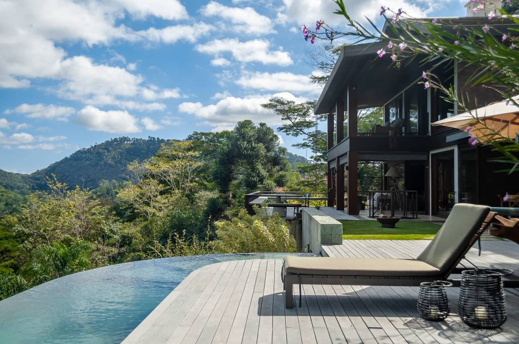 Casa de campo com piscina de borda infinita e deck de madeira.