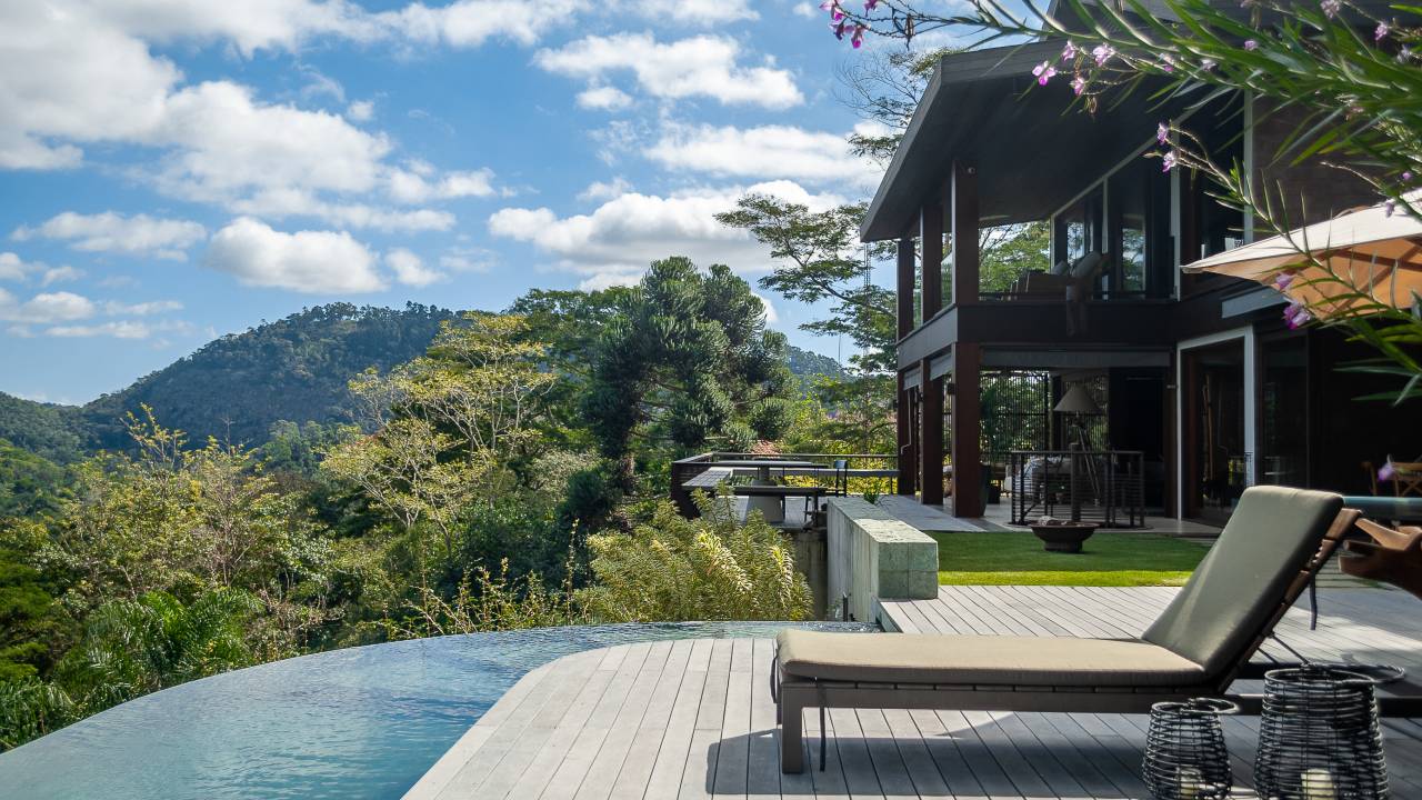 Casa de campo com piscina de borda infinita e deck de madeira.