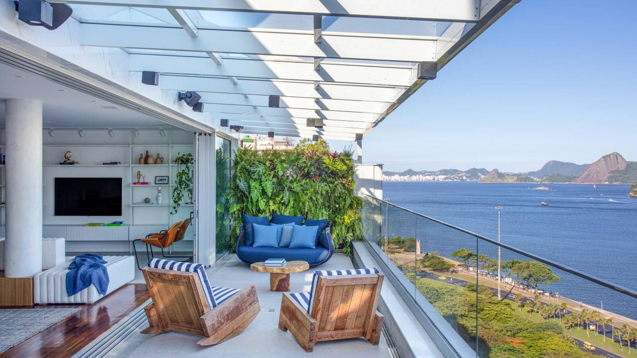 Varanda com vista para Pão de Açúcar; poltronas e sofá azul e jardim vertical.