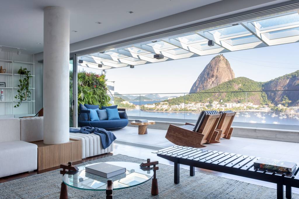 cobertura-320m-varanda-integrada-portico-muxarabi-studio-plano-arquitetura-06 Varanda com vista para Pão de Açúcar; poltronas e sofá azul e jardim vertical.