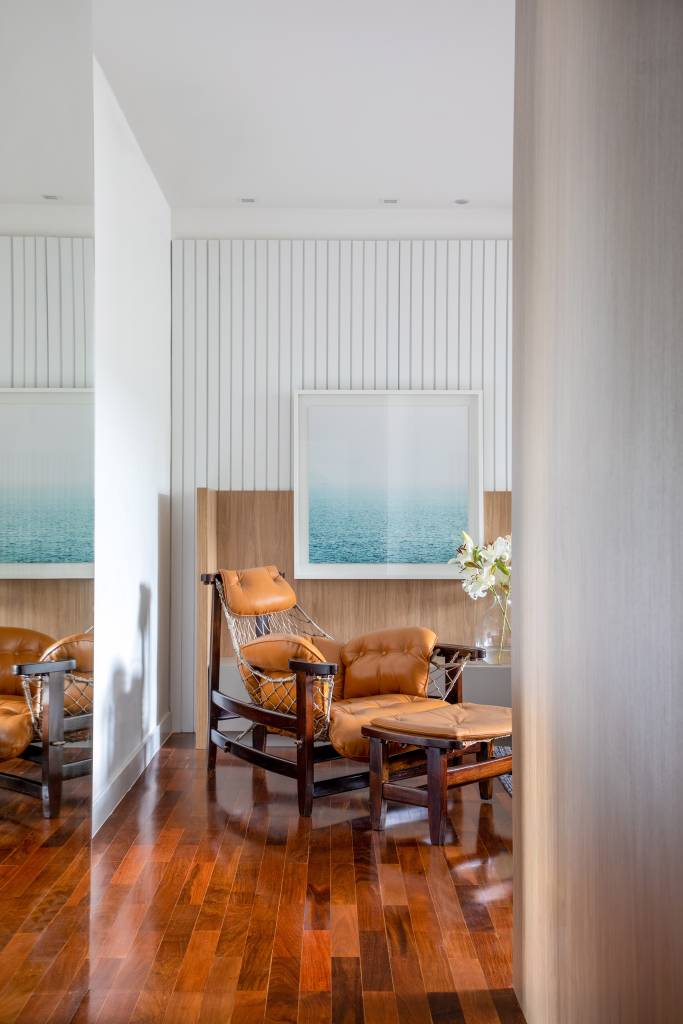 cobertura-320m-varanda-integrada-portico-muxarabi-studio-plano-arquitetura-25-poltrona-jangada Sala de estar clara com parede ripada e poltrona Jangada.