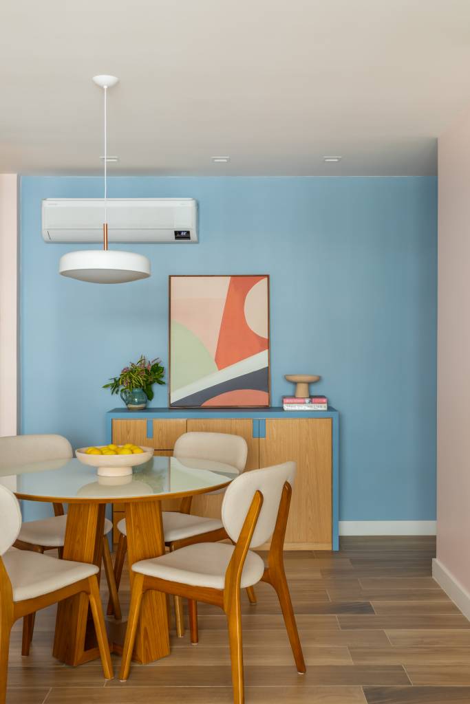alegre-colorido-ape-80m-estante-vazada-cozinha-sala-colab-juntos-arquitetura-09-jantar Sala de jantar com parede azul, mesa de jantar redonda, cadeiras com estofamento branco.