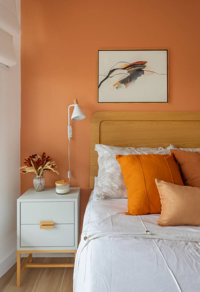 alegre-colorido-ape-80m-estante-vazada-cozinha-sala-colab-juntos-arquitetura-15-quarto Quarto com parede laranja, cama de casal, armário com porta branca e cabeceira de madeira.