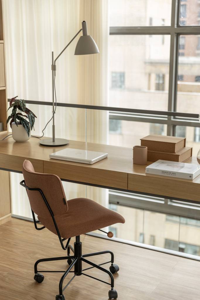 Apê de 110 m² com pé-direito duplo vira duplex com mezanino metálico Apê de 110 m² com pé-direito duplo vira duplex com mezanino metálico. Na foto, mezanino com home office e vista para a janela.