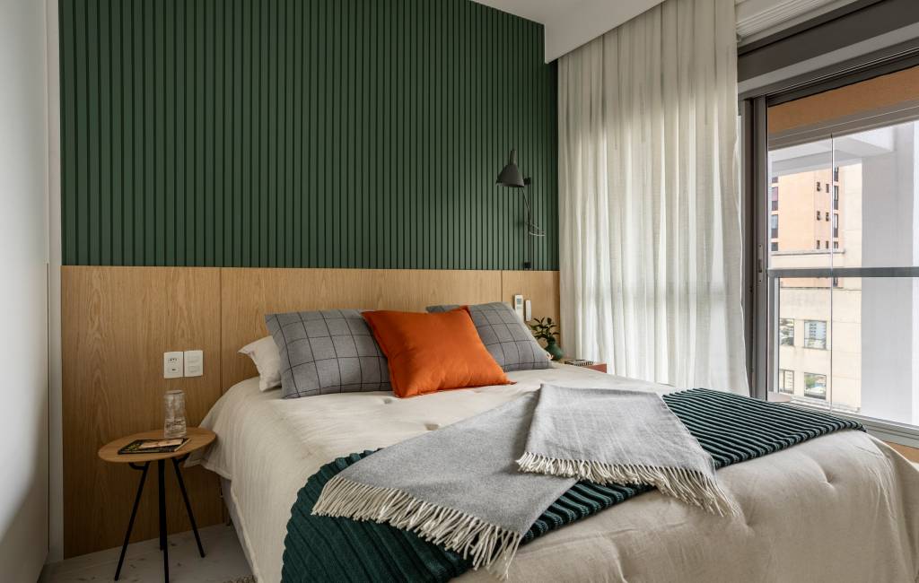 Apê de 110 m² com pé-direito duplo vira duplex com mezanino metálico Apê de 110 m² com pé-direito duplo vira duplex com mezanino metálico. Na foto, quarto de casal com parede ripada verde e cabeceira de madeira.