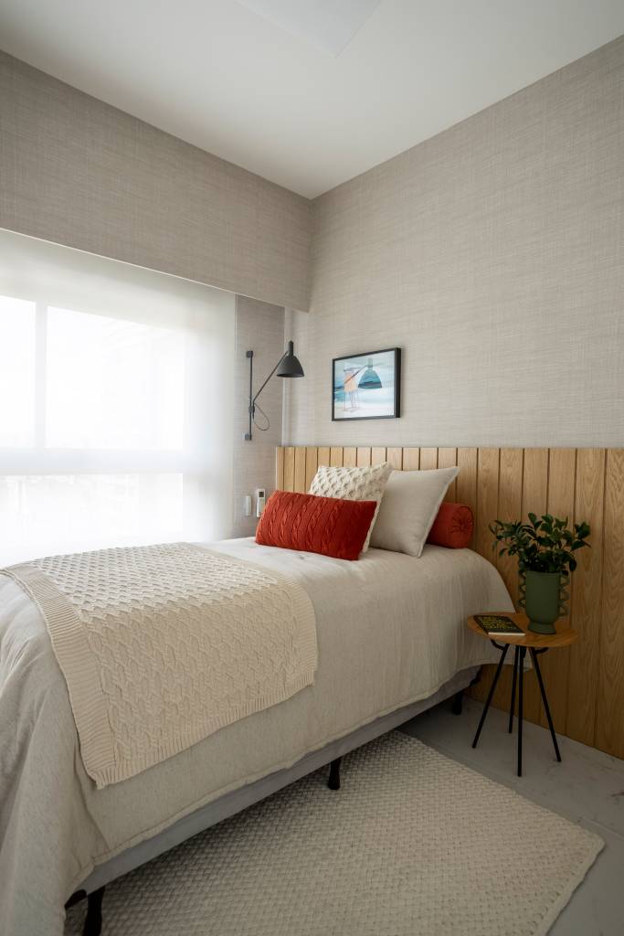 Apê de 110 m² com pé-direito duplo vira duplex com mezanino metálico Apê de 110 m² com pé-direito duplo vira duplex com mezanino metálico. Na foto, quarto de hóspedes com cabeceira de madeira e tapete.