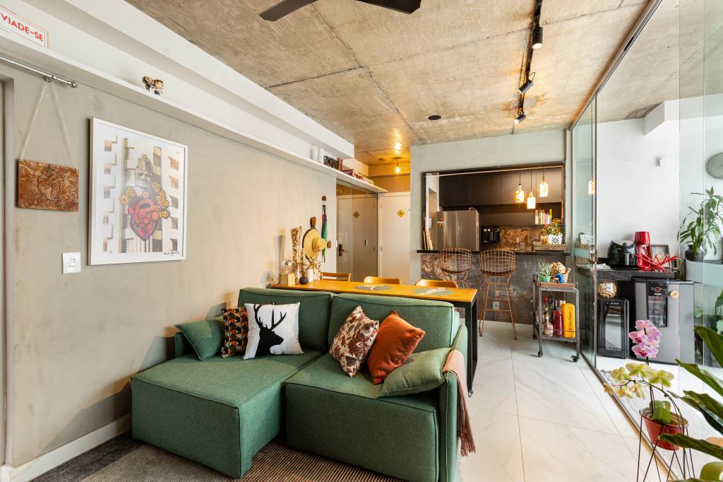 ape-120m-sofa-verde-tijolinho-porcelanato-varanda-spa-grupo-arquitetos-urbanistas-01 Sala de estar integrada com cozinha com sofá verde, aparador de madeira e cozinha preta ao fundo.