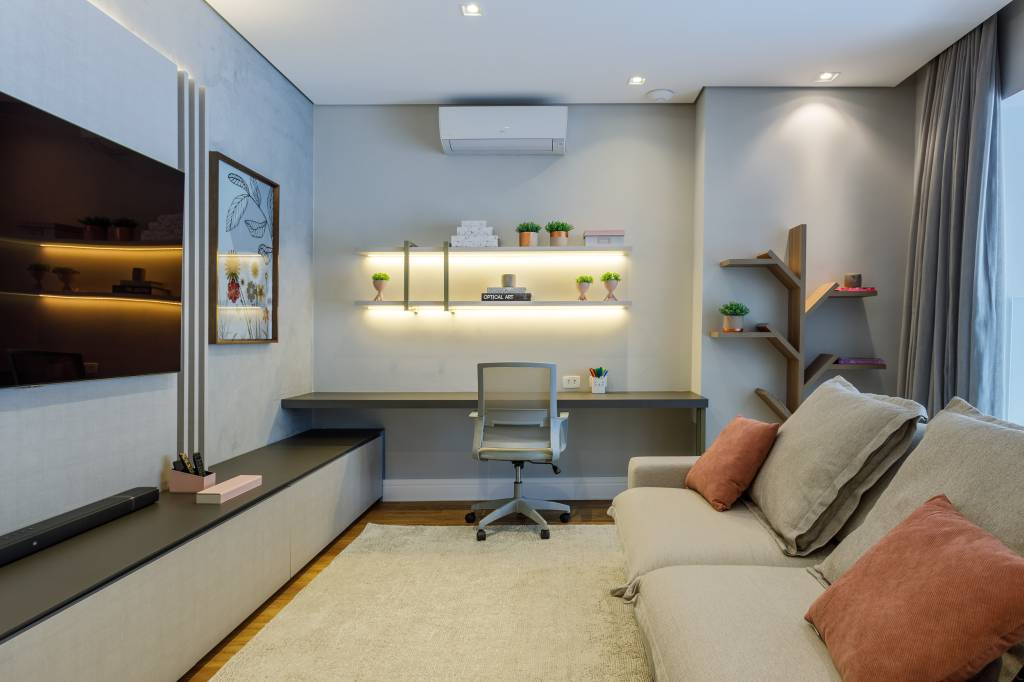 ape-180m-decoracao-neutra-pe-direito-duplo-mezanino-infinity-spaces-01 Mezanino com tv, tapete branco, sofá claro e bancada com prateleiras.