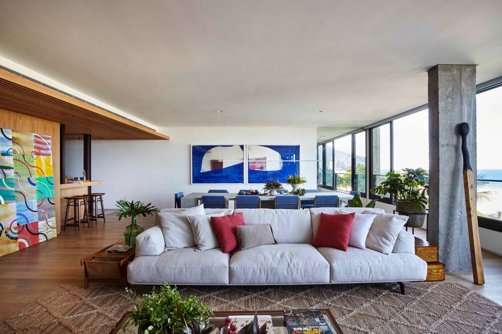 ape-350m-academia-quarto-de-hospedes-escala-arquitetura-01-sala-janela Sala de estar com janela grande, sofá cinza, tapete e mesa de centro. Sala de jantar integrada.