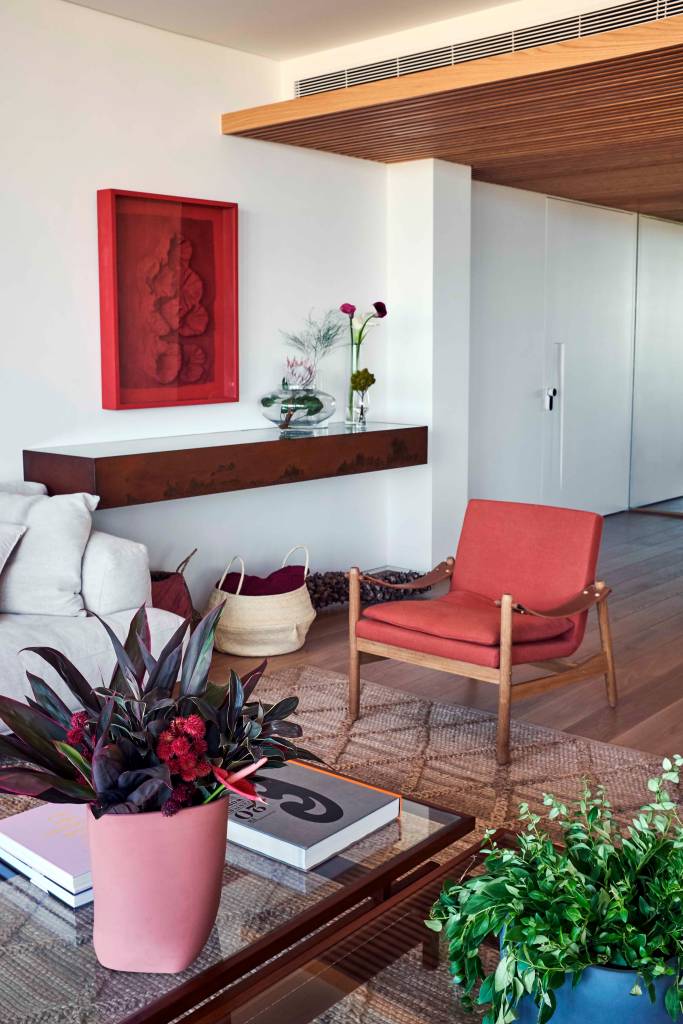 ape-350m-academia-quarto-de-hospedes-escala-arquitetura-05-sala-vaso Sala de estar com mesa de centro com vasos e poltrona vermelha.