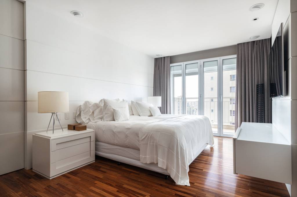 como-montar-um-ambiente-minimalista-jeito-facil-dantas-e-passos-arquitetura-01 Quarto minimalista com piso de madeira, cama de casal, mesa lateral e piso de madeira.