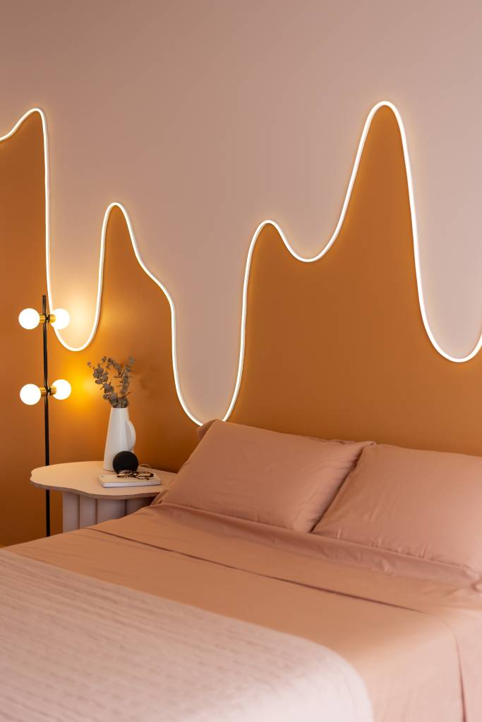 Quarto com parede em tons terrosos e fita de led