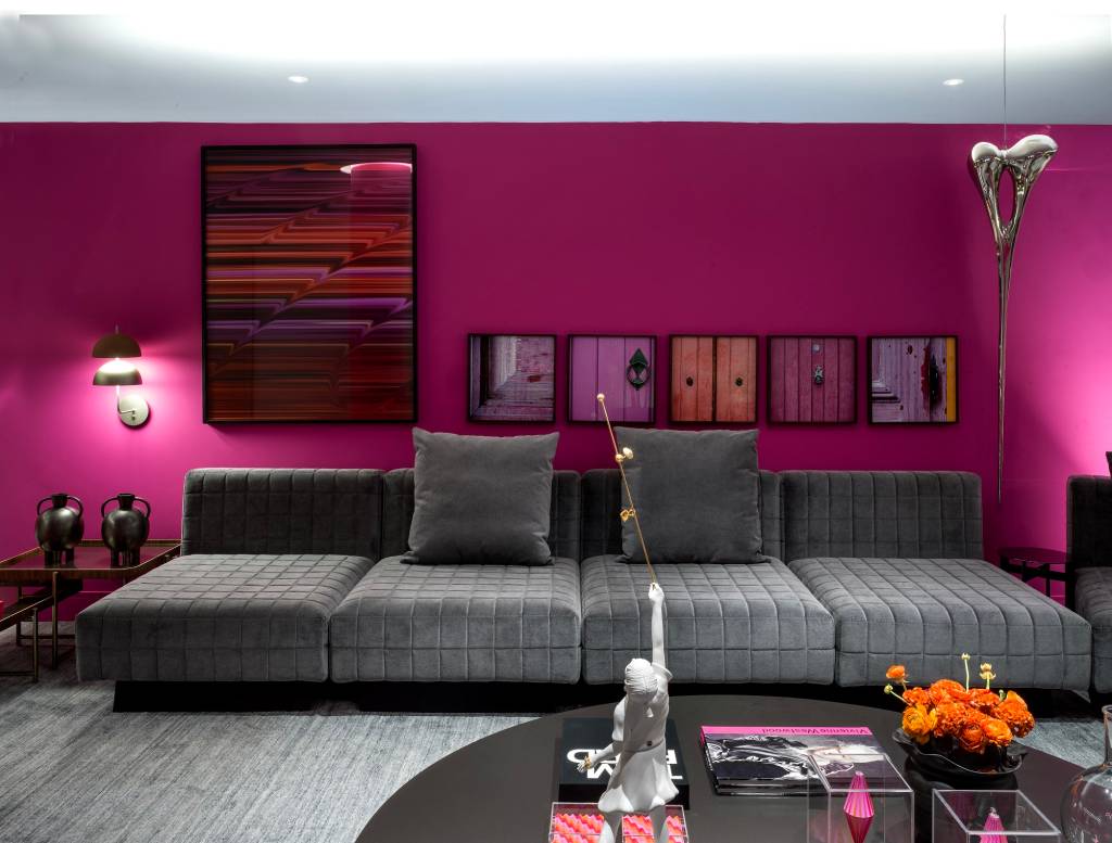 metaverso-cores-vibrantes-marcam-loft-brunete-fraccaroli-casacor-sao-paulo-2023-06 Sala com sofá de veludo cinza, tapete cinza e parede rosa.