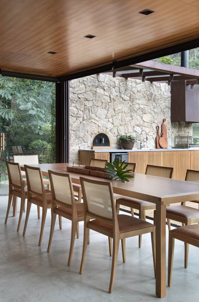 paineis-lisos-ripados-de-madeira-freijo-revestem-casa-campo-300m-diego-raposo-arquitetos-15-jantar Sala de jantar com parede ripada de madeira e mesa de jantar de madeira grande.