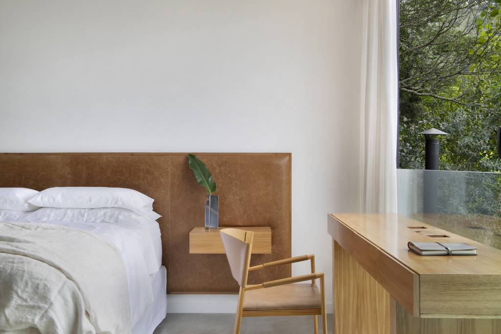 paineis-lisos-ripados-de-madeira-freijo-revestem-casa-campo-300m-diego-raposo-arquitetos-19-quarto-home-office Quarto com cama de casal, cabeceira de couro e home office