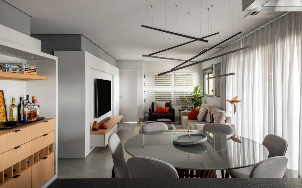 ape-155m-paleta-de-cores-sobria-cozinha-forma-u-sotaque-arquitetura-04 Sala de tv integrada com jantar e cozinha com piso de porcelanato cinza e mesa redonda.