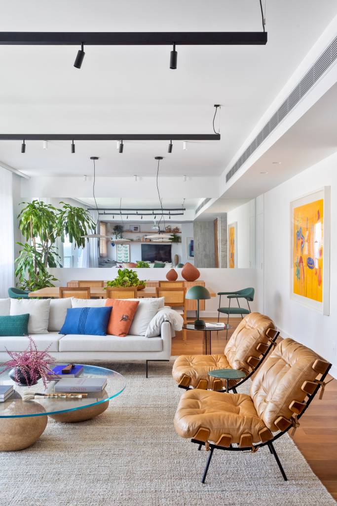 ape-190m-copa-parede-azul-cadeiras-alaranjadas-escala-arquitetura-02-sala Sala de estar com tapete bege, poltronas costela, sofá branco com almofadas coloridas e cadeira azul.