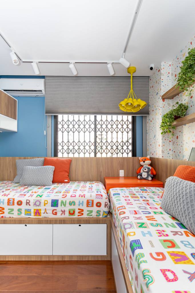 azul-pontua-hall-marcenaria-cozinha-ape-150m-livia-ornellas-21-quarto-infantil Quarto infantil com duas camas de solteiro com roupa de cama colorida e parede azul.