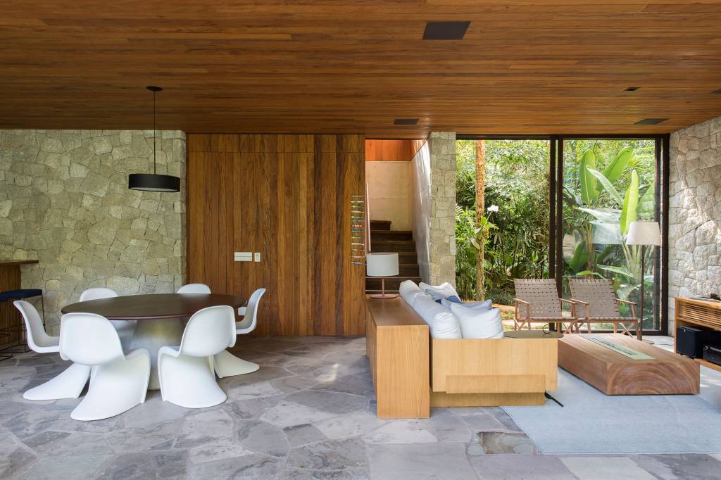 casa-153-m2-camufla-natureza-litoral-paulista-daniel-fromer-credito-maira-acayaba (14) Casa de 153 m² se camufla em meio à natureza do litoral paulista. Projeto de Daniel Fromer, interiores de Julyana Bortolotto. Na foto, sala de estar com parede de vidro e escada.