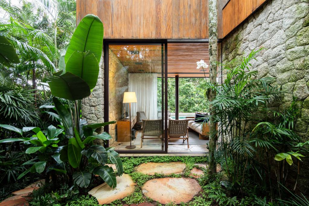 casa-153-m2-camufla-natureza-litoral-paulista-daniel-fromer-credito-maira-acayaba (22) Casa de 153 m² se camufla em meio à natureza do litoral paulista. Projeto de Daniel Fromer, interiores de Julyana Bortolotto. Na foto, sala de estar com parede de vidro.