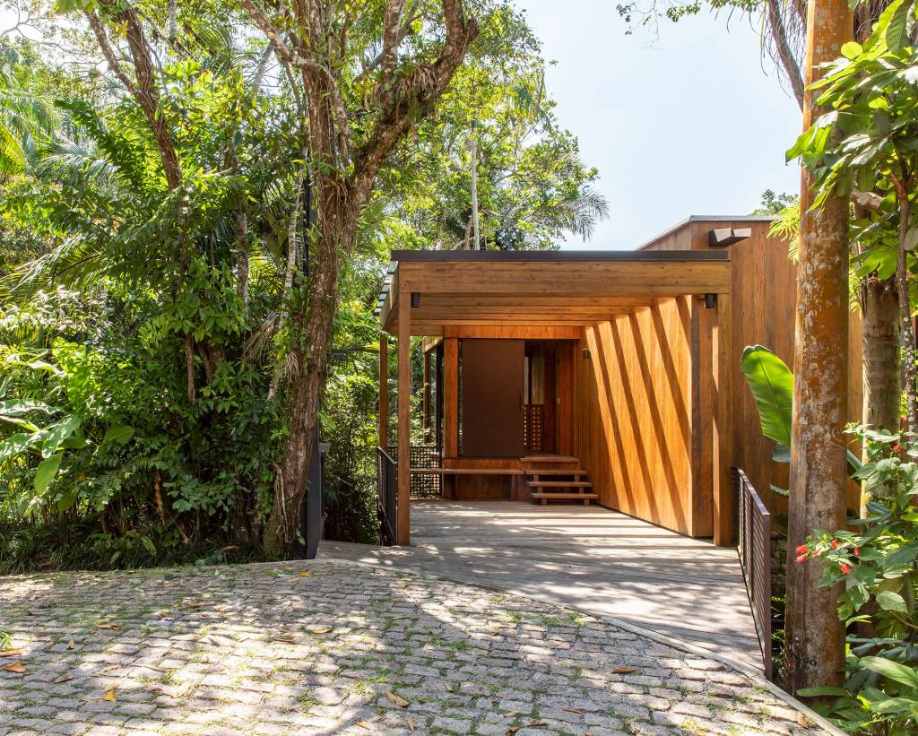 casa-153-m2-camufla-natureza-litoral-paulista-daniel-fromer-credito-maira-acayaba (3) Casa de 153 m² se camufla em meio à natureza do litoral paulista. Projeto de Daniel Fromer, interiores de Julyana Bortolotto. Na foto, entrada da casa com pergolado e vista para o jardim.