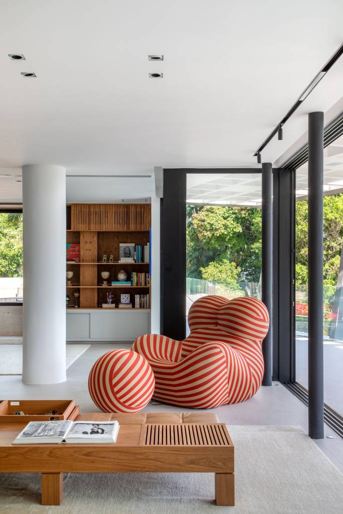 Sala de estar com janelas grandes e poltrona com pufe.