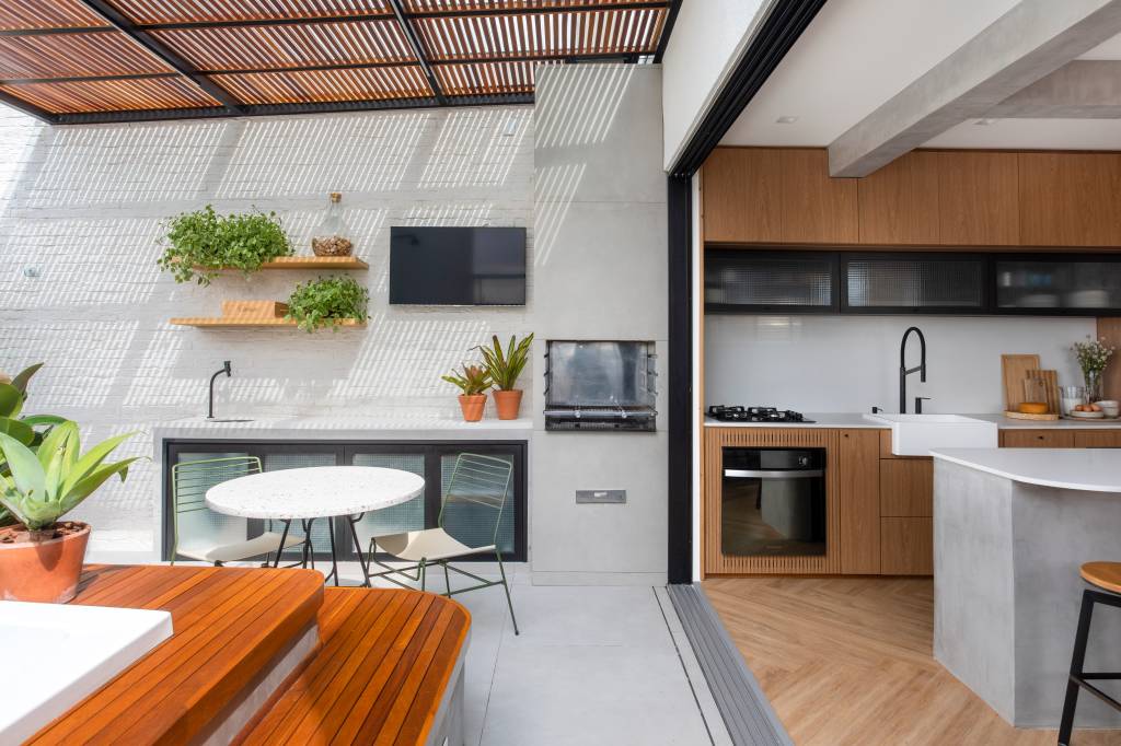 cobertura-linear-85m-area-gourmet-banheira-hidromassagem-amaisg-arquitetura-03-varanda Varanda integrada com estar; área gourmet com churrasqueira, mesa redonda e hidromassagem.