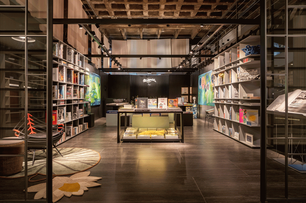 livraria-clima-intimista-repleta-arte-brasileira-nana-cunha-caru-cunha-silvia-camargo-casacor-sp-credito-rafael-renzo (3) Esta livraria tem clima intimista e repleta de arte brasileira. Projeto de Nana Cunha, Caru Cunha e Sílvia Camargo para a CASACOR SP 2023. Na foto, estantes com livros, paredes escuras e quadros.