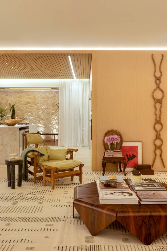 quiet-luxury-feng-shui-indiano-loft-120-m2-bianca-da-hora-credito-mca-estudio (12) Quiet luxury e feng shui indiano marcam este loft de 120 m², Projeto de Bianca Da Hora Arquitetura para a CASACOR SP 2023. Na foto, sala de estar com mesa de centro, poltrona, tapete e cozinha integrada.