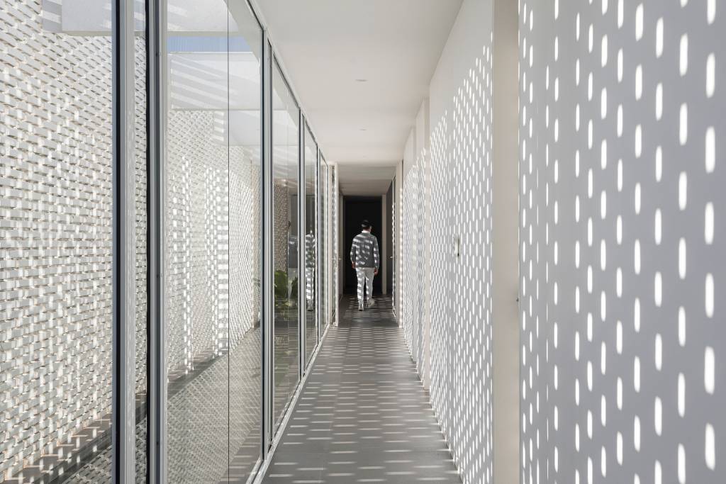 tijolos-vazados-brancos-compoem-fachada-casa-600-m2-brasilia-bloco-arquitetos-credito-joana-franca (4) Tijolos vazados brancos compõem a fachada desta casa de 600 m² em Brasília. Projeto de Bloco Arquitetos. Na foto, corredor com efeito de luz provocado pela parede de tijolos vazados.
