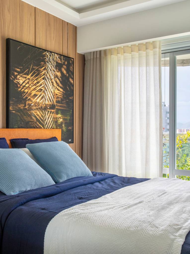tons-terracota-automacao-marcam-ape-167m-virna-carvalho-12 Quarto com cama de casal, cortina e parede revestida de madeira com quadro.