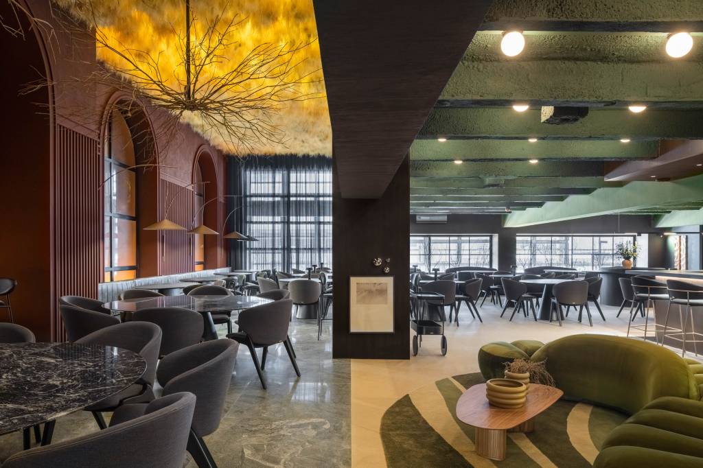 50 mil hastes de aspargos secos adornam o teto deste restaurante. Projeto de Renan Altera para a CASACOR SP 2023. NA foto, visão com teto verde e de aspargos, mesa, cadeira e sofá.