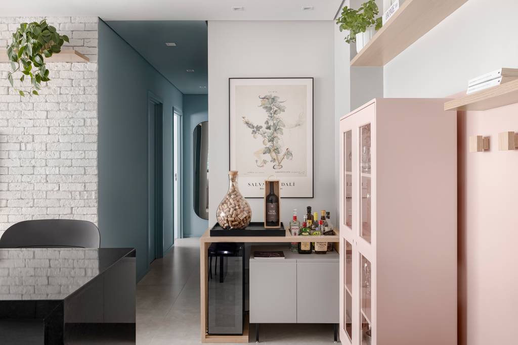 Apê de 84 m² ganha décor delicado em tons de azul, verde e rosa. Projeto de Dani Espírito Santo. Na foto, hall com pintura meia-parede, banco e cristaleira rosa. Bar e quadro.
