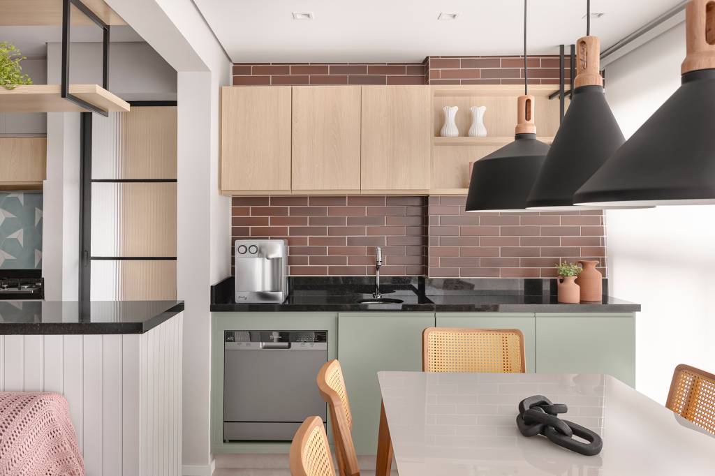 Apê de 84 m² ganha décor delicado em tons de azul, verde e rosa. Projeto de Dani Espírito Santo. Na foto, varanda gourmet com parede com ceramica que imita tijolinho, mesa e marcenaria verde.
