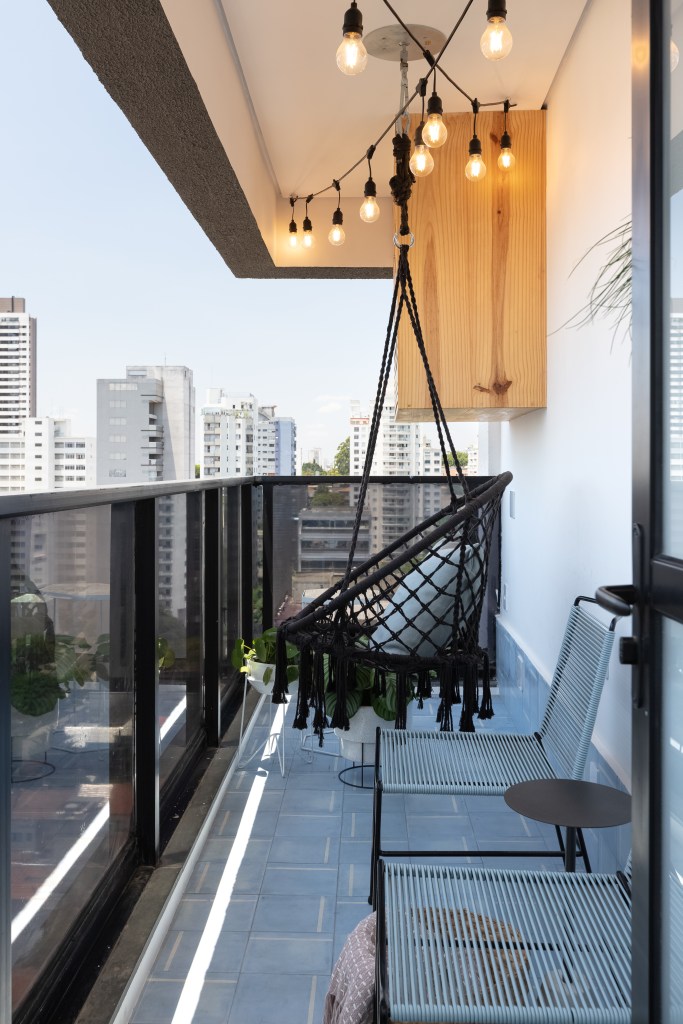 Varanda com piso colorido azul, balanço de macramê preto, cadeiras azuis, plantas e horta suspensa.