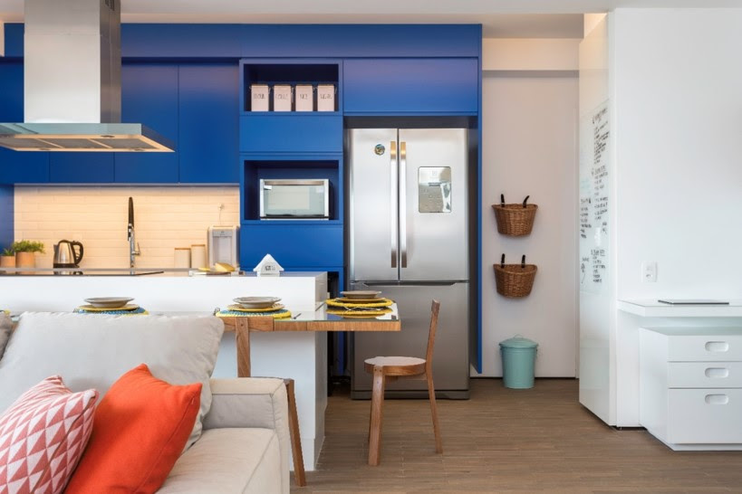 atmosfera-personalizada-apes-com-a-mesma-planta-studio-tan-gram-03 Cozinha integrada com marcenaria azul e ilha branca com bancada de madeira.