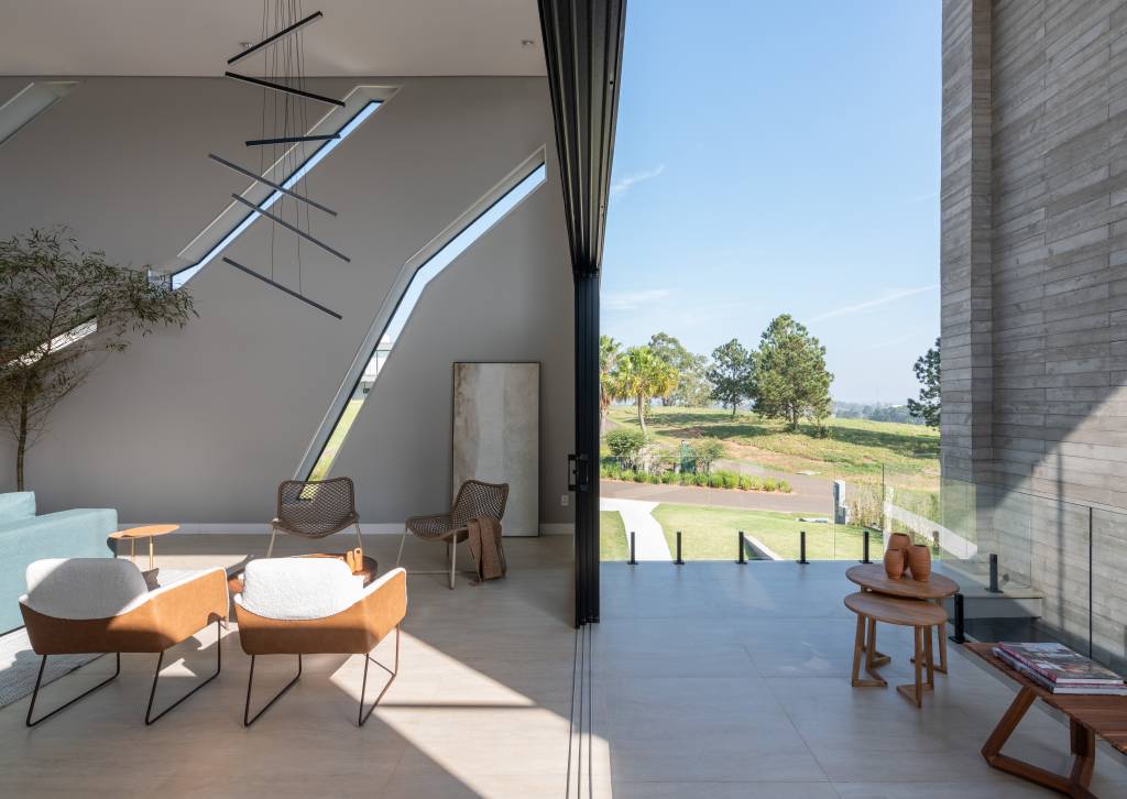 casa-interiores-sobrios-aberturas-assimetricas-fachada-12-sala Sala minimalista com piso de porcelanato, pé-direito alto e poltrona branca.