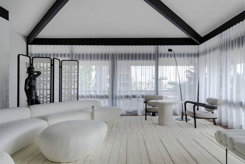 living-minimalista-85-m2-decor-branco-preto-cinza-areia-david-bastos-credito-gabriela-daltro (6) Living minimalista de 85 m² ganha décor em branco, preto, cinza e areia. Projeto de David Bastos para a CASACOR Bahia. Na foto, sala de estar com sofá curvo, estante preta, espelho e tapete.