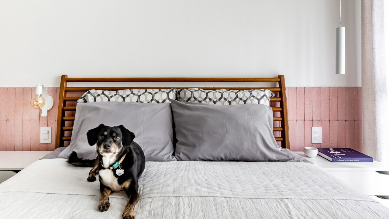 Quarto com cama de casal e cabeceira rosa.