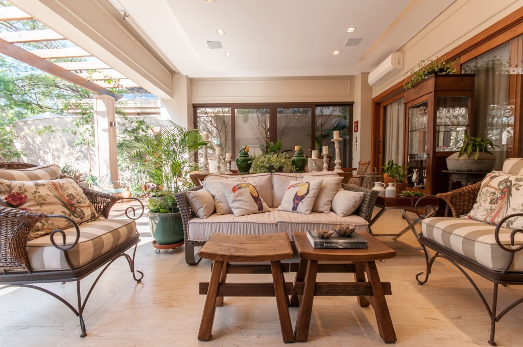 Sala de estar integrada com jardim e banquetas de madeira como mesa de centro.