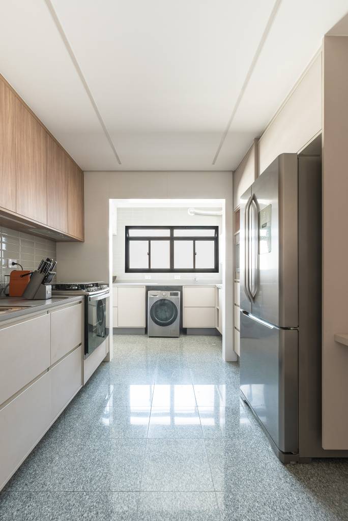 painel-de-madeira-ripada-destaque-area-social-ape-120m-clareira-arquitetura-16-cozinha-lavanderia Projeto de Clareira Arquitetura. Na foto, cozinha com piso de granito, marcenaria bege e backsplash de azulejos. Lavanderia ao fundo.