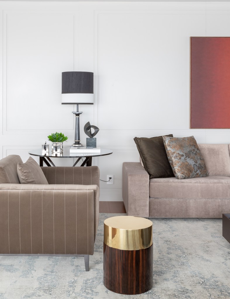 Sala de estar em tons neutros com sofá marrom claro, mesa de centro e quadro vermelho.