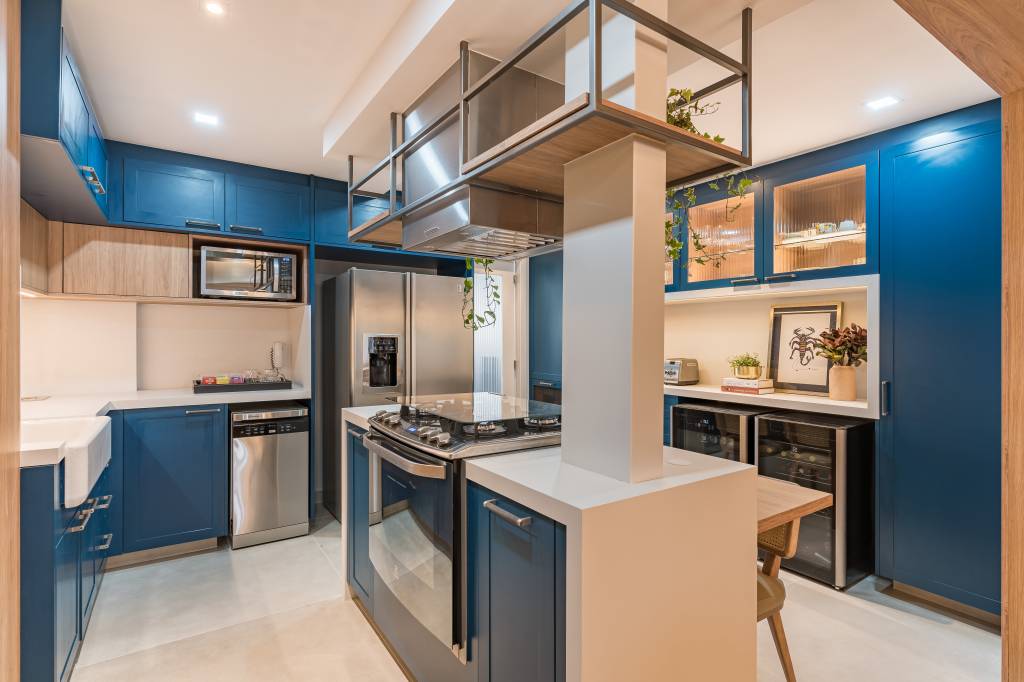 reforma-cria-suite-closet-integrado-spaco-interior-09-cozinha-azul Cozinha com piso de porcelanato, ilha e marcenaria azul; armários com portas de vidro.