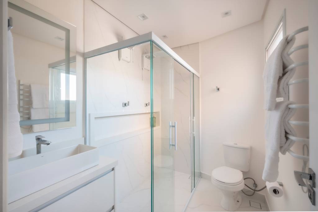 reforma-integra-aproveita-ape-110m-com-planta-irregular-pb-arquitetura-11-banheiro Projeto de PB Arquitetura. Na foto, banheiro branco com armário branco e box de vidro.