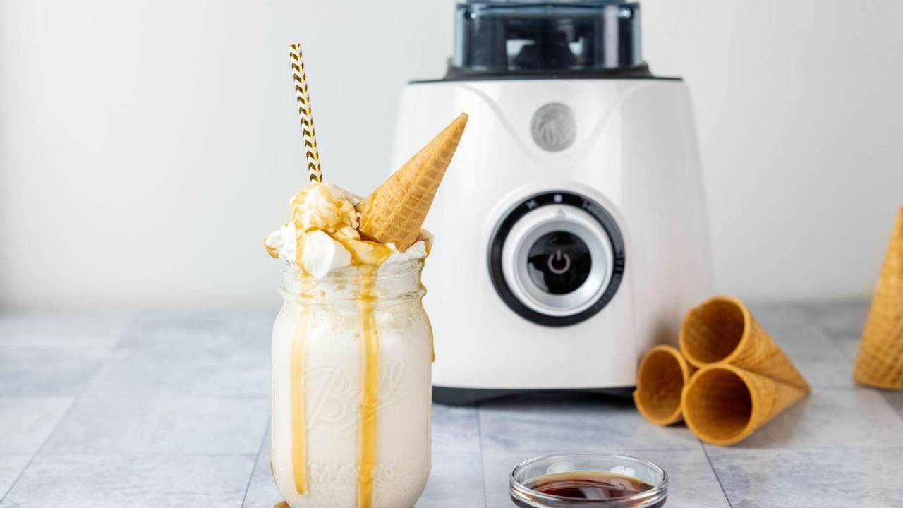 Milkshake de waffle em mason jar com liquidificador ao fundo.