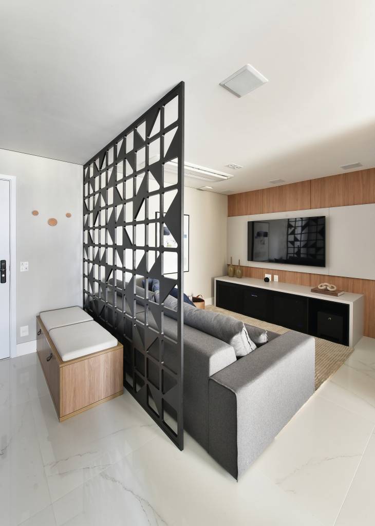 divisoria-de-ambientes-vantagens-delimitar-sem-separar-rosangela-pena-03 Projeto de Rosângela Pena. Na foto, sala de estar e sala de tv com divisória vazada atrás de sofá.